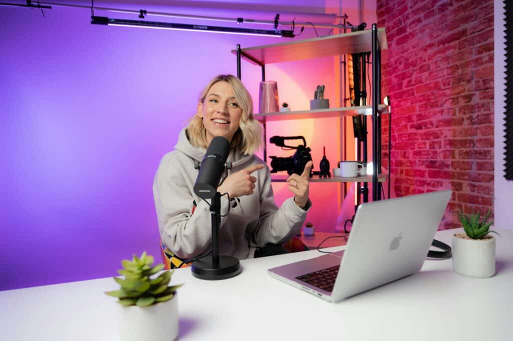 Smiling content creator recording a podcast with a microphone and camera in a colorful studio